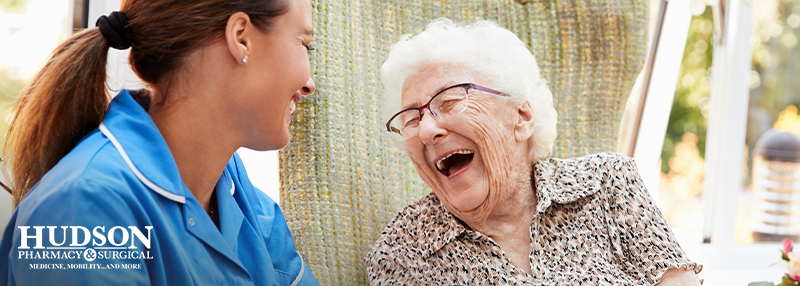 Senior woman laughing outdoors with facility caregiver