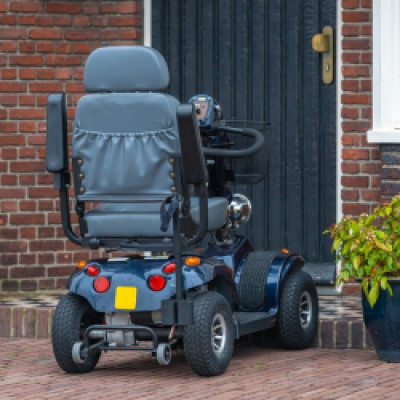A mobility scooter parked outside a brick building. The building is residential and there