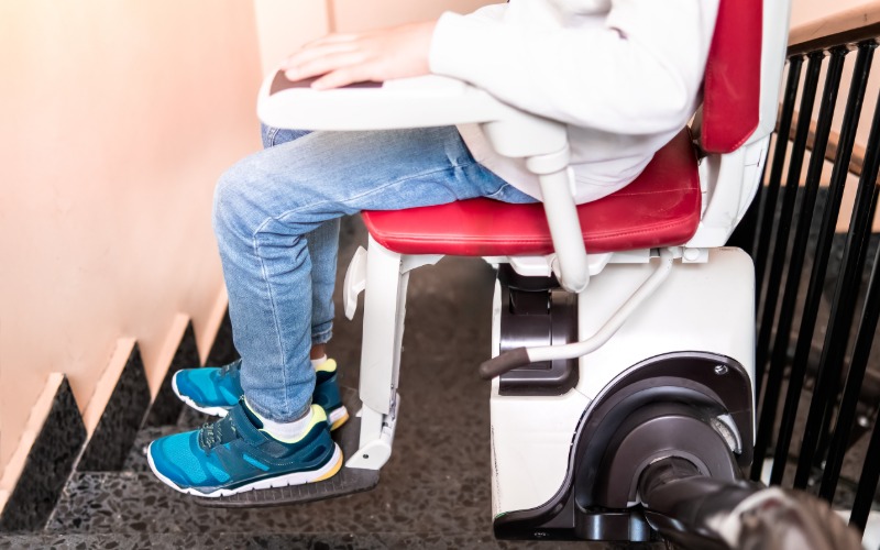 A close-up of a stairlift at the top of the stairs getting ready to take a young child down the stairway.